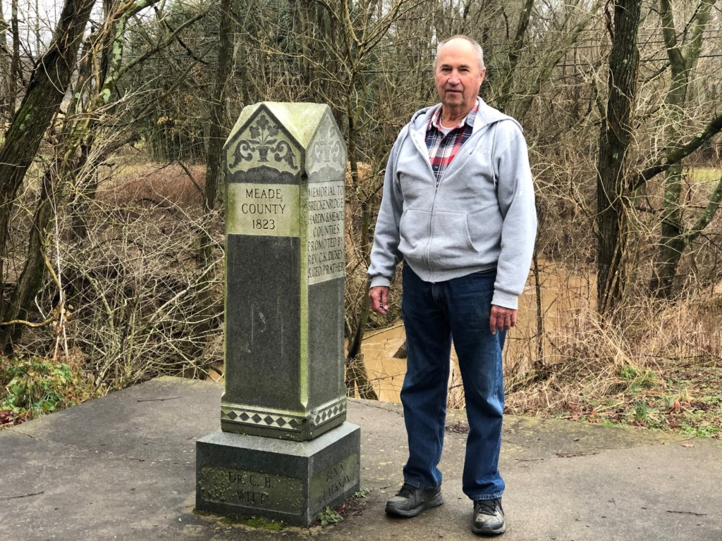 Buddy Rosenberger next to marker where Meade, Breckinridge and Hardin Counties meet in Big Spring, KY